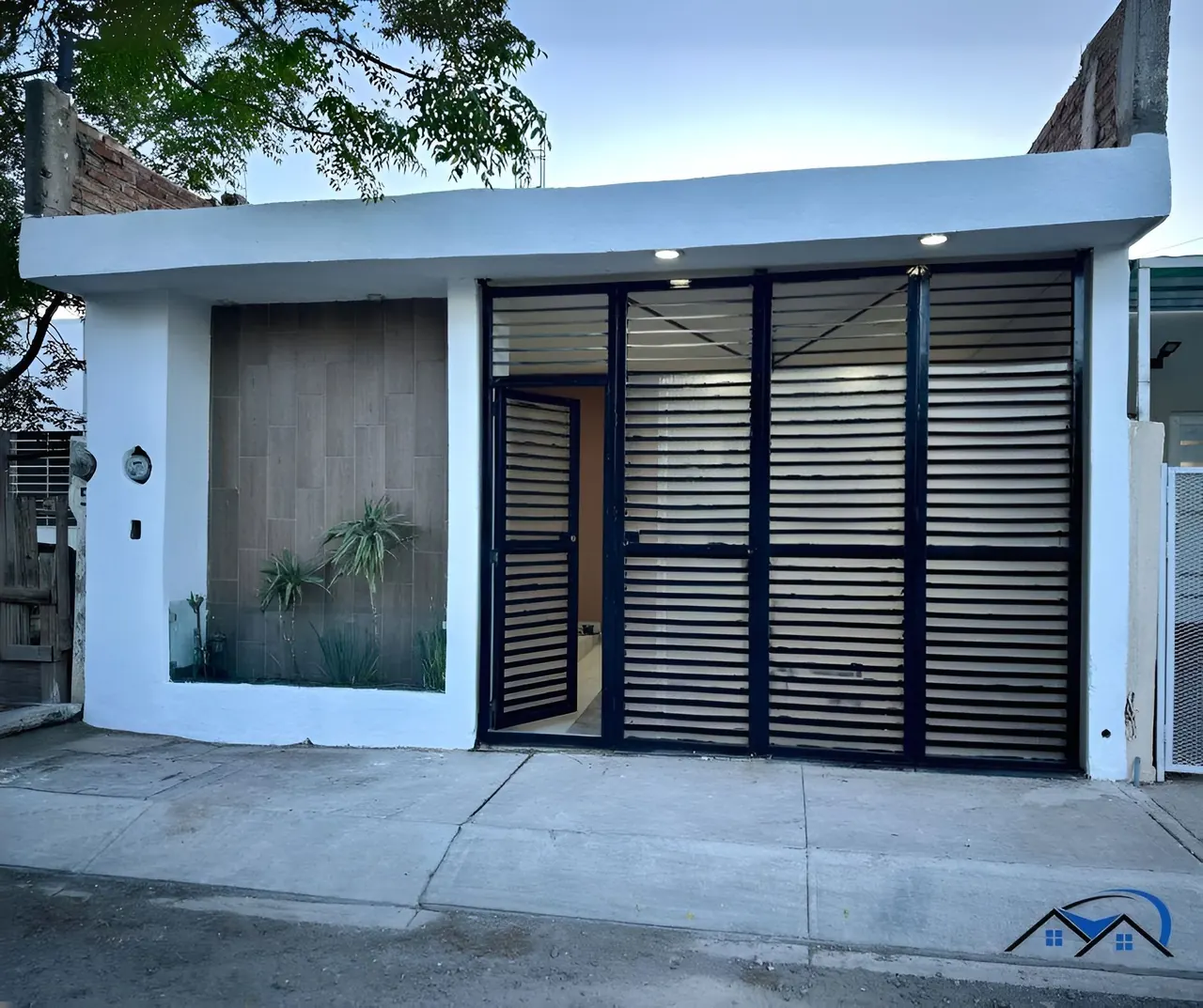 Fachada de la casa en Villas de Guadalupe, con portón de herrería y jardinera